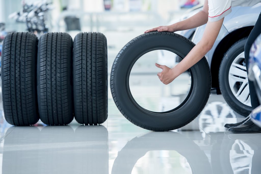 Technician holding tire beside stacked tires
